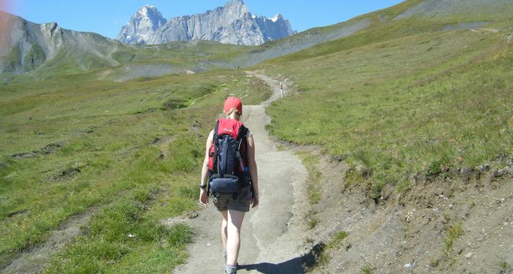 Femme en train de faire une randonnée sur un sentier de montagne avec une vue panoramique.