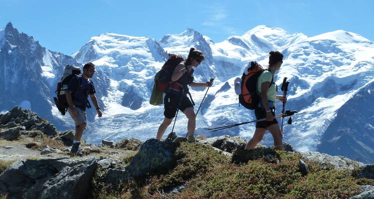 Randonneurs marchant le long d'une crête de montagne aux sommets enneigés.