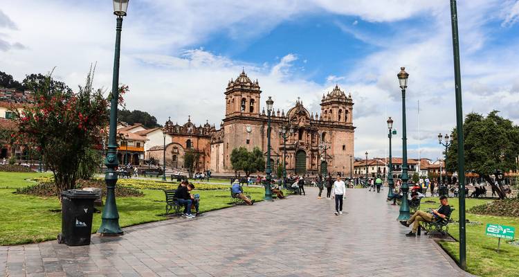 Plaza con una catedral, personas caminando por un sendero de piedra.