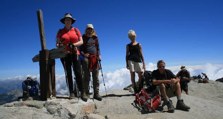 Grupo de excursionistas posando en la cima de una montaña.