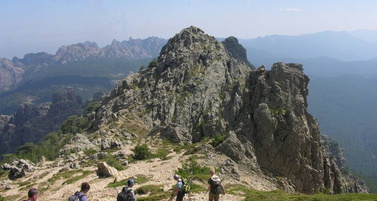 Senderistas caminando por la cresta de una montaña rocosa.