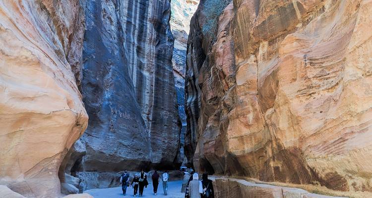 Bezoekers lopen door de smalle, roodachtige zandstenen Siq die naar Petra leidt.