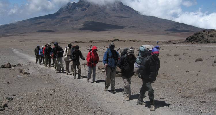 Eine Gruppe von Wanderern auf einem Wanderweg mit einem Berg im Hintergrund.