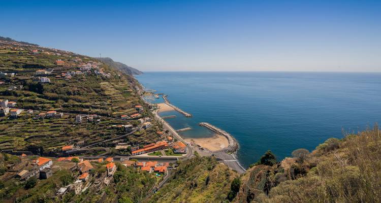 Vue côtière d'une ville avec un front de mer, des bâtiments et des collines.