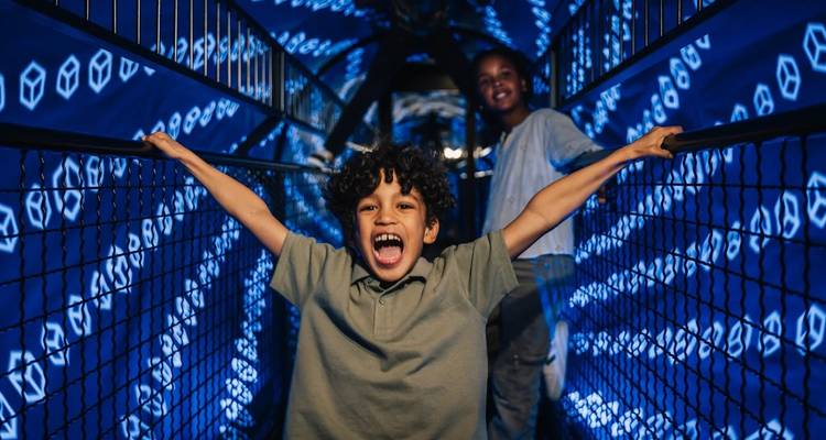 Excited child on an illuminated bridge in an interactive exhibit.