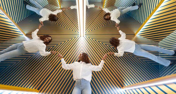 Artistic mirror exhibit reflecting a woman in multiple poses.