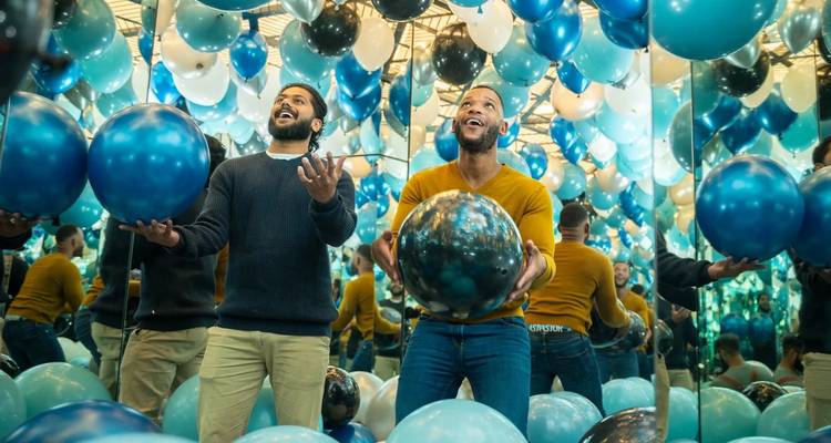 Two men enjoying an interactive ball exhibit with mirrors.