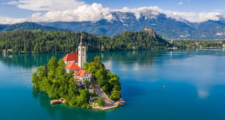 Ikonische kirchengekrönte Insel in den smaragdgrünen Gewässern des Bleder Sees mit den Julischen Alpen im Hintergrund
