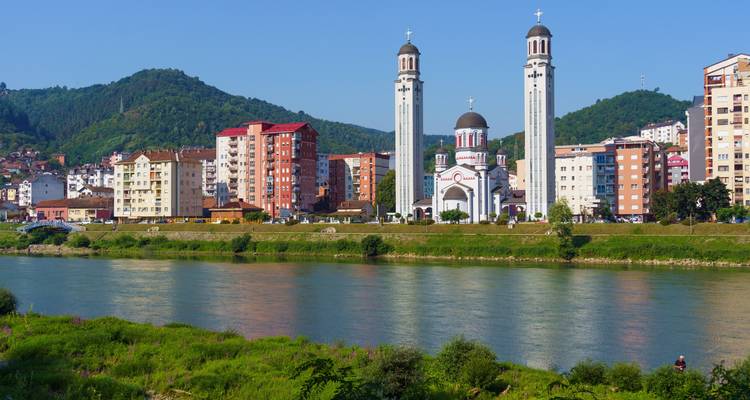 Moderne Flussufer-Skyline mit zweiturmiger Kirche und Wohnblöcken in Sremska Mitrovica