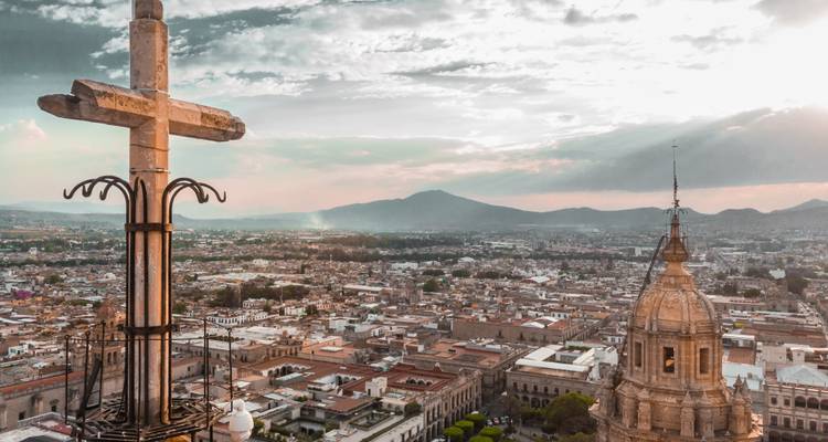 Vue panoramique de la ville avec une croix et l'horizon au coucher du soleil.