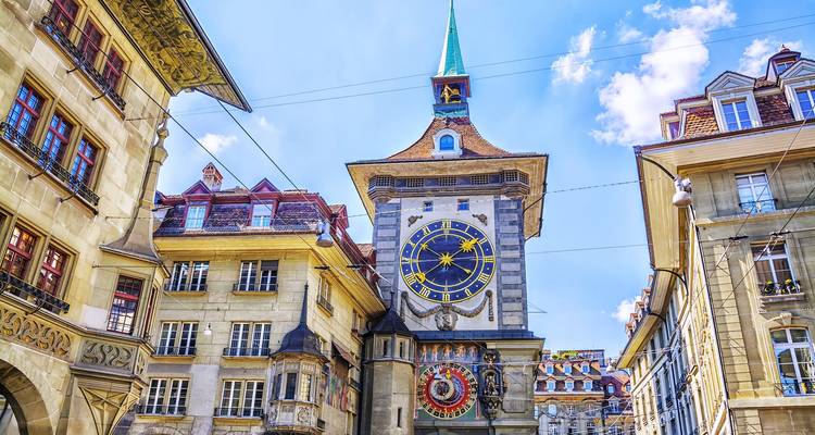 Historic clock tower surrounded by ornate Swiss buildings under sunny sky