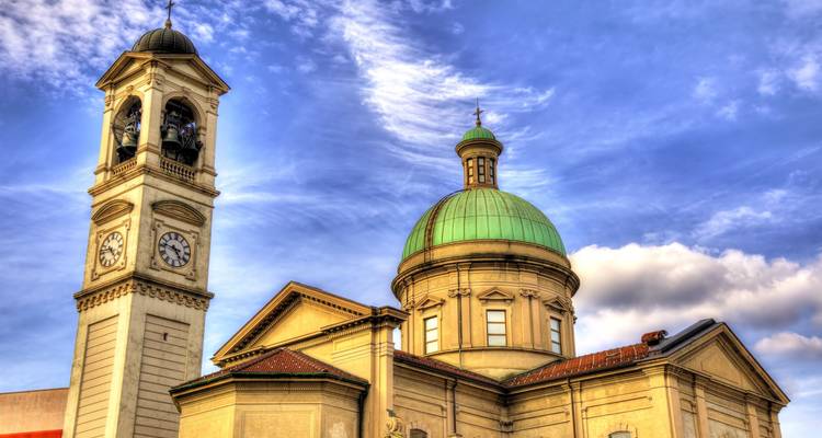 Church with green copper dome and adjacent bell tower against dramatic skies