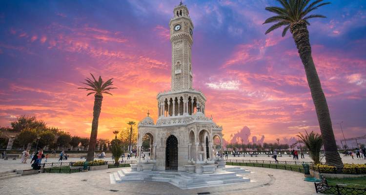 The elegant Izmir Clock Tower glowing under a fiery sunset sky in Konak Square.