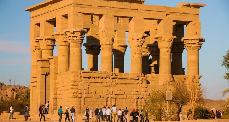 Turistas caminando frente a un antiguo templo egipcio.