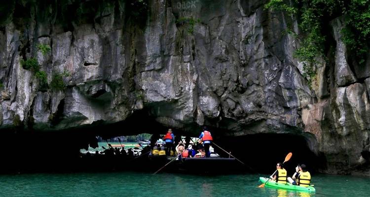 Tourists in life vests paddling through a cave.