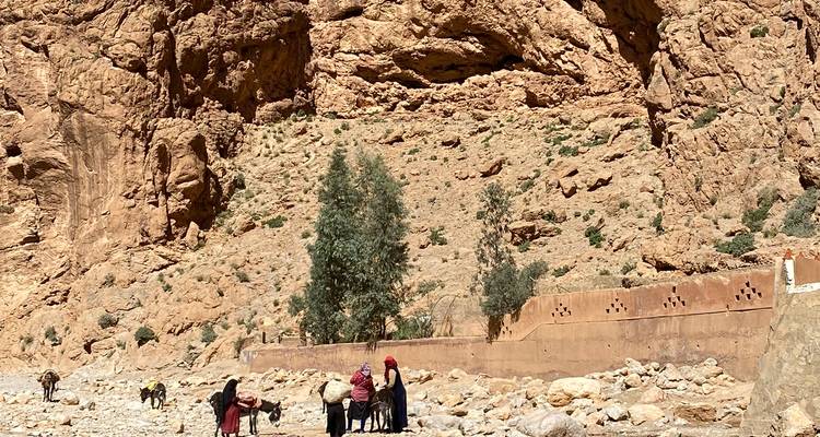 Lokale bewoners en lastdieren die over de rotsachtige bodem van een dramatische canyon onder hoge rotswanden lopen.