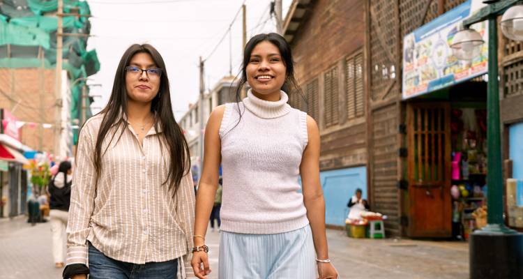 Deux personnes marchant dans une rue bordée de magasins.