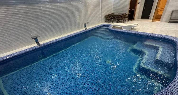 Una pequeña piscina cubierta con mesas y sillas cerca.