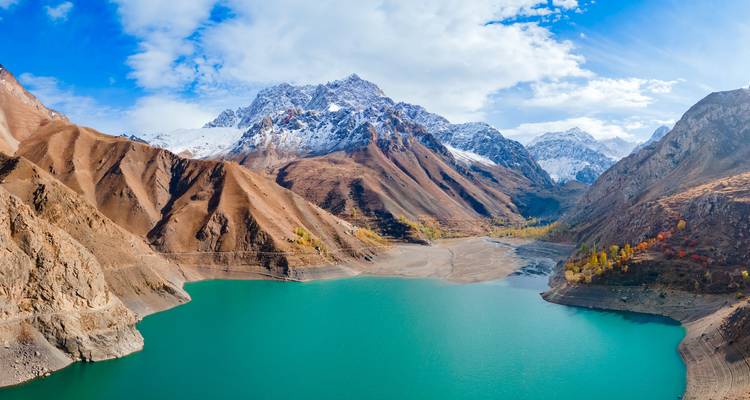 Un paisaje impresionante con un lago turquesa rodeado de montañas cubiertas de nieve.