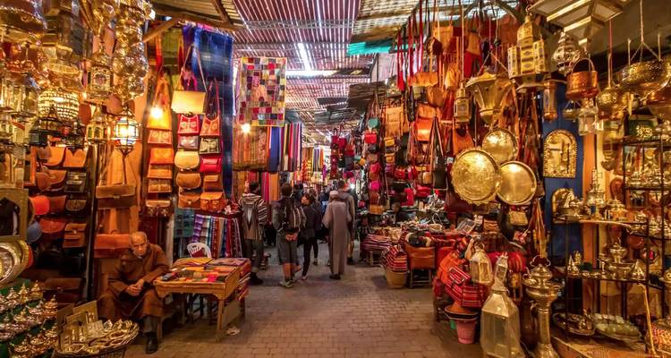 Busy Moroccan market with people and colorful textiles.