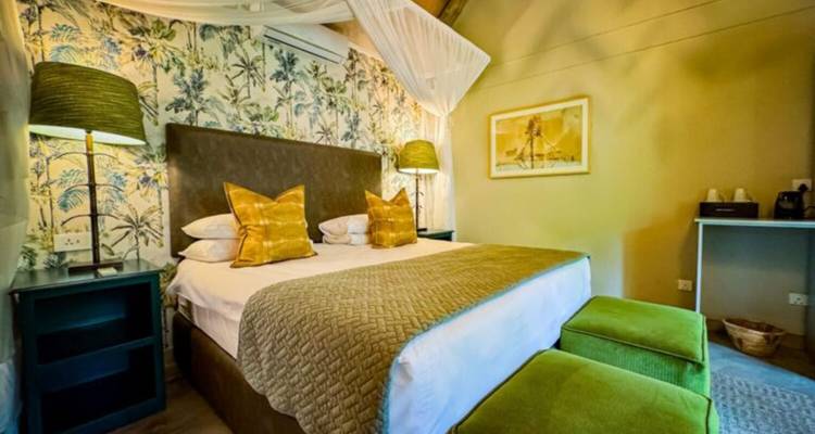 Komfortables Safari-Lodge-Schlafzimmer mit Moskitonetz und gemusterter Tapete.