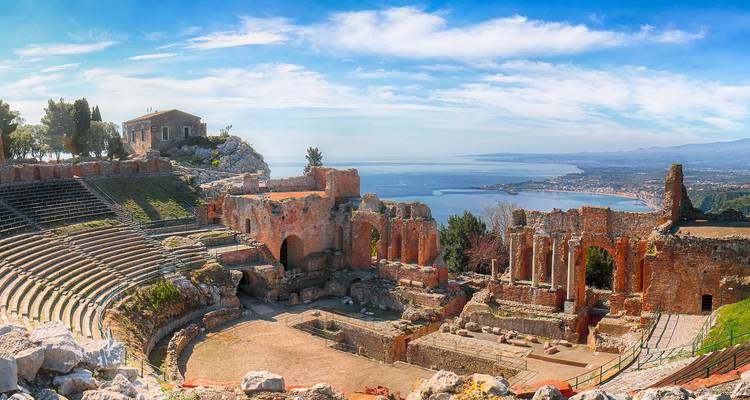 Ruïnes van het oude Griekse theater in Taormina met uitzicht op de blauwe baai van Naxos.