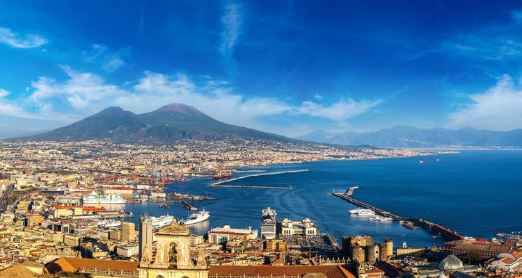 Panorámica del horizonte de Nápoles con el Monte Vesubio dominando la bahía bajo cielos azules y despejados.
