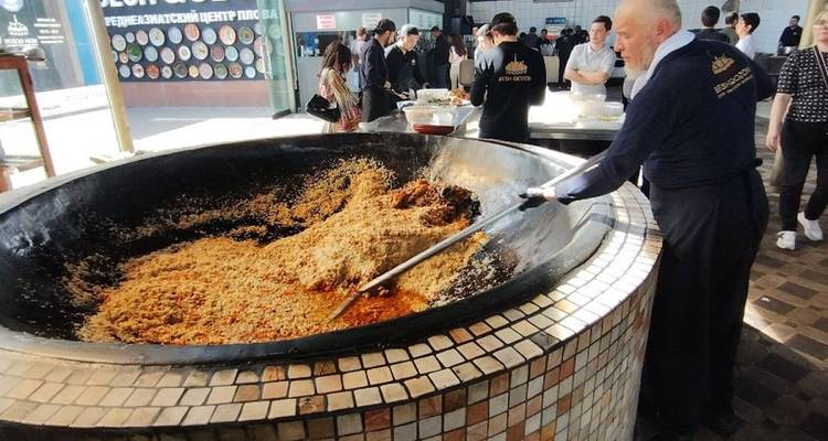 Un homme cuisinant un plat de riz traditionnel dans une grande poêle