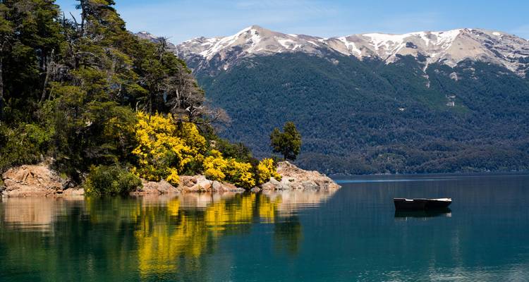 Lac avec toile de fond de montagne et un petit bateau.