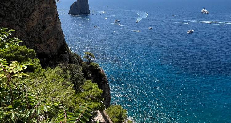 Océano azul con barcos y acantilados a la vista.