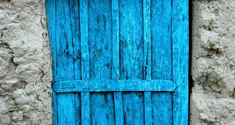 Puerta azul vibrante en una pared de piedra rústica.