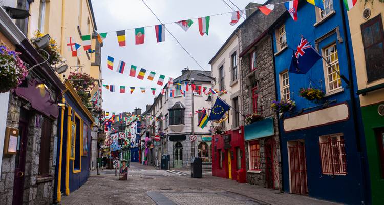 Colorful street in a town with flags and hanging decorations.