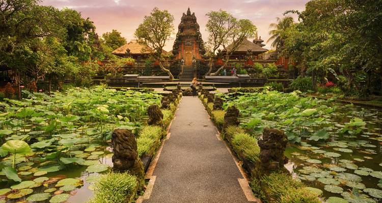 Camino sobre estanque de loto que lleva al patio del Templo Saraswati al atardecer en Ubud, Bali.