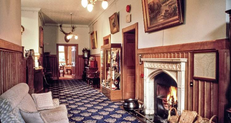 Gezellige houten hal van een landelijke lodge met een brandende open haard en antieke decoratie