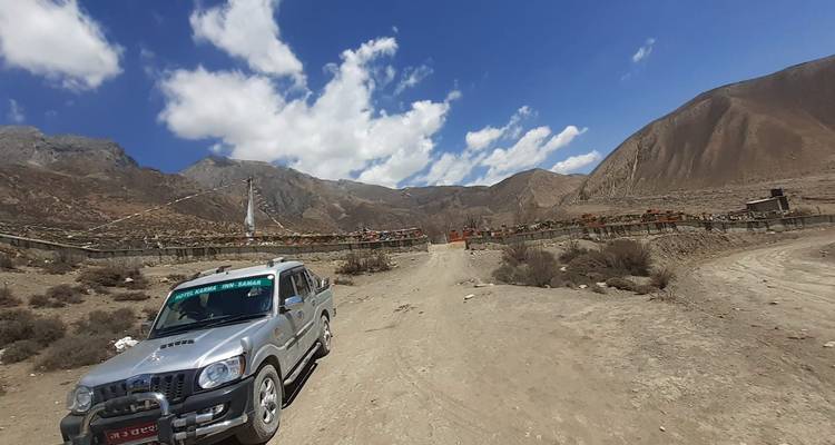 Un véhicule garé sur une route de terre dans une région montagneuse.