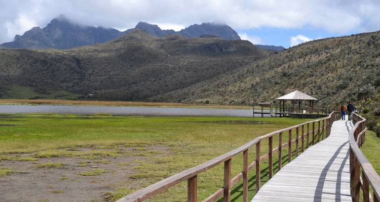 Pasarela de madera que conduce a un refugio con montañas de fondo
