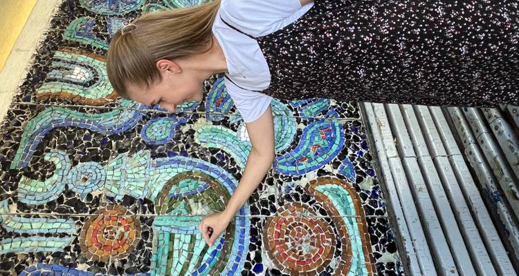 Femme interagissant avec une peinture murale colorée.