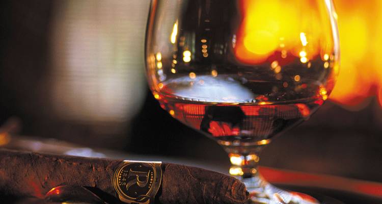 Verre d'alcool et cigare près d'un feu chaleureux.