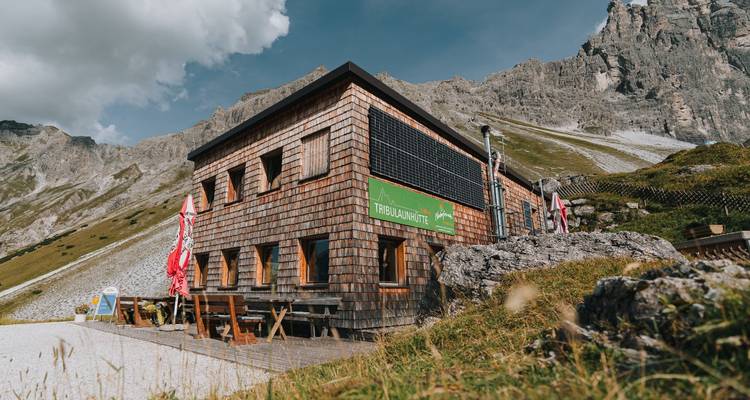 Un chalet de montagne avec des pics escarpés en arrière-plan.