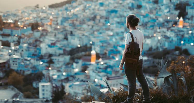 Un hombre parado en una colina con vista a una ciudad al anochecer.