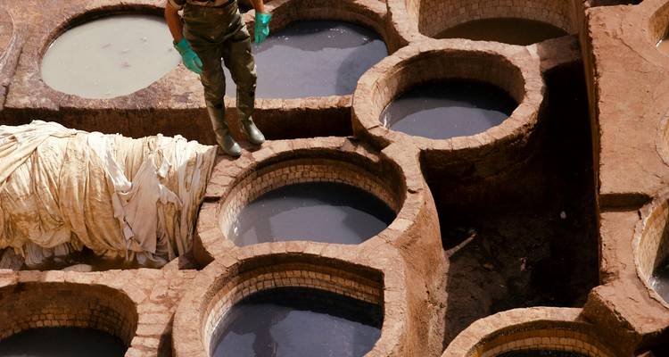 Tenería tradicional con hombre de pie entre las tinas de teñido.