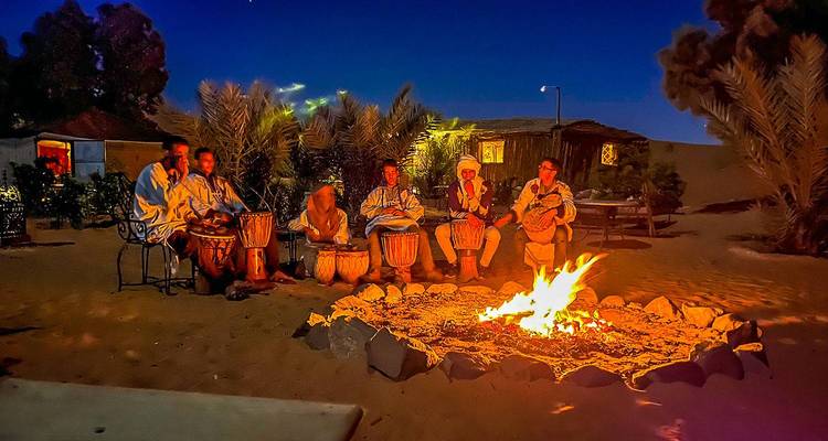 Grupo de personas sentadas alrededor de una fogata bajo un cielo nocturno.