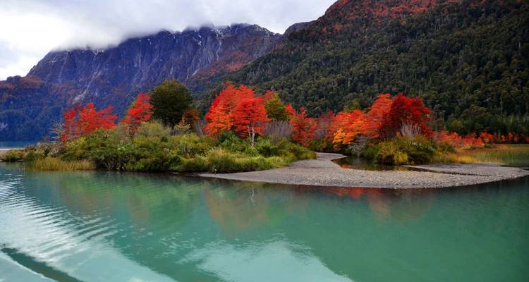 Les feuilles d'automne et les montagnes se reflètent dans un lac tranquille.