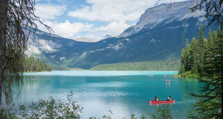 Canoa roja en un lago con montañas al fondo.