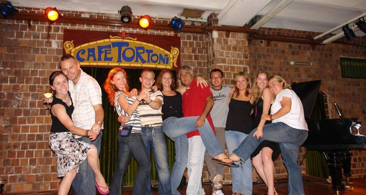 Gelukkige tourgroep poseert op het podium in het historische Café Tortoni tango-etablissement.