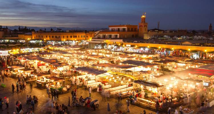 Panorama nocturne des étals de nourriture de Marrakech illuminés sur la place Jemaa el-Fnaa.