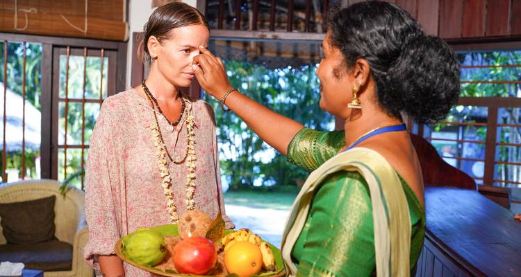 Femme recevant un accueil traditionnel indien avec des offrandes de fruits.