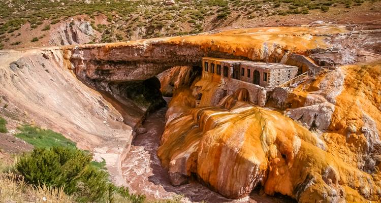 Pont naturel rocheux avec des dépôts minéraux orange et jaune vifs.