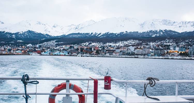 Vue depuis un bateau regardant vers une ville avec des montagnes en arrière-plan.