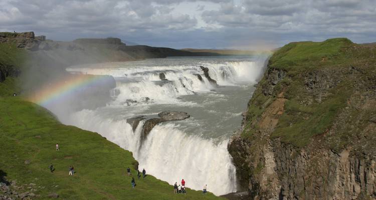 Mighty Gullfoss waterfall plunging into a canyon with a rainbow arching through mist in Iceland.